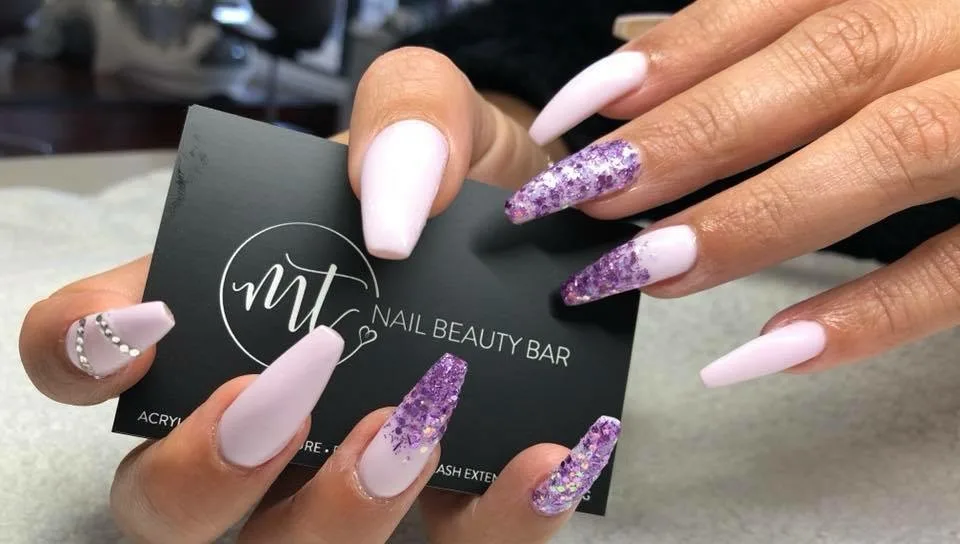 Lilac coffin nails with amethyst glitter, holding an MT business card